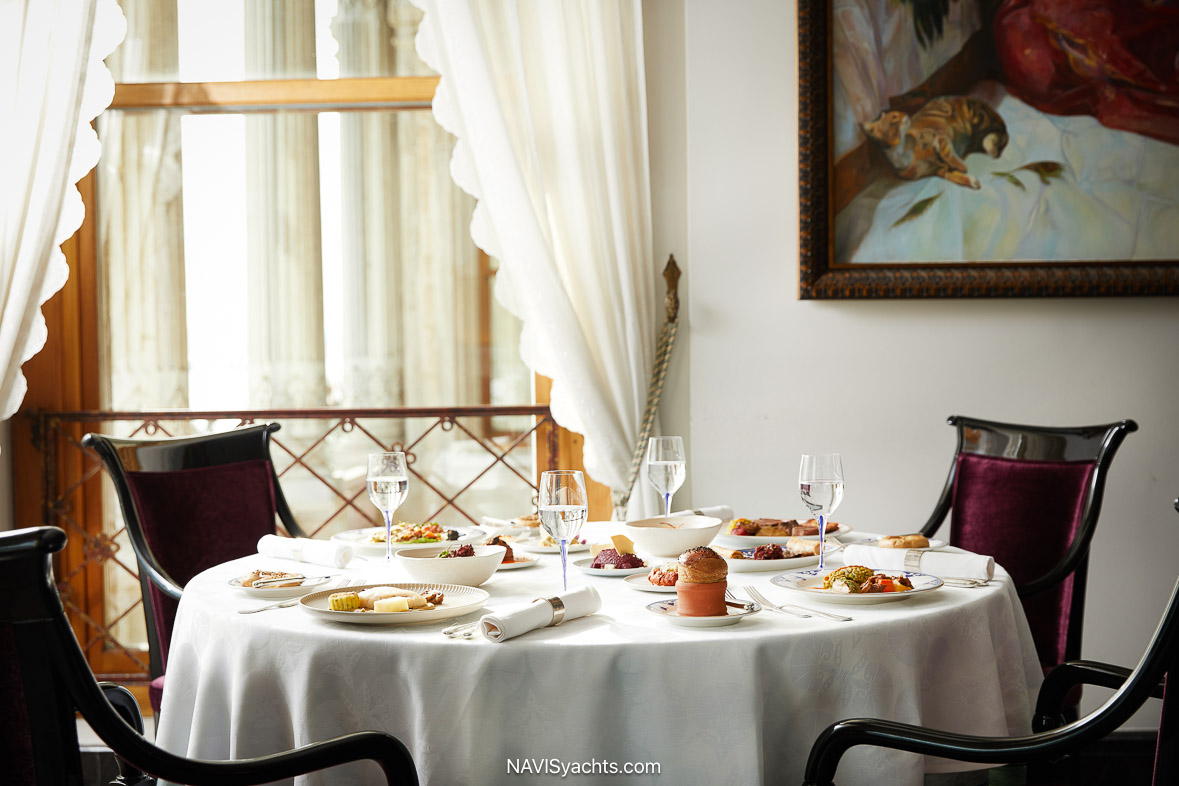 Elegant dining table set for a meal at Tuğra Restaurant, Çırağan Palace Kempinski Istanbul, with marble columns and luxurious decor in the background.