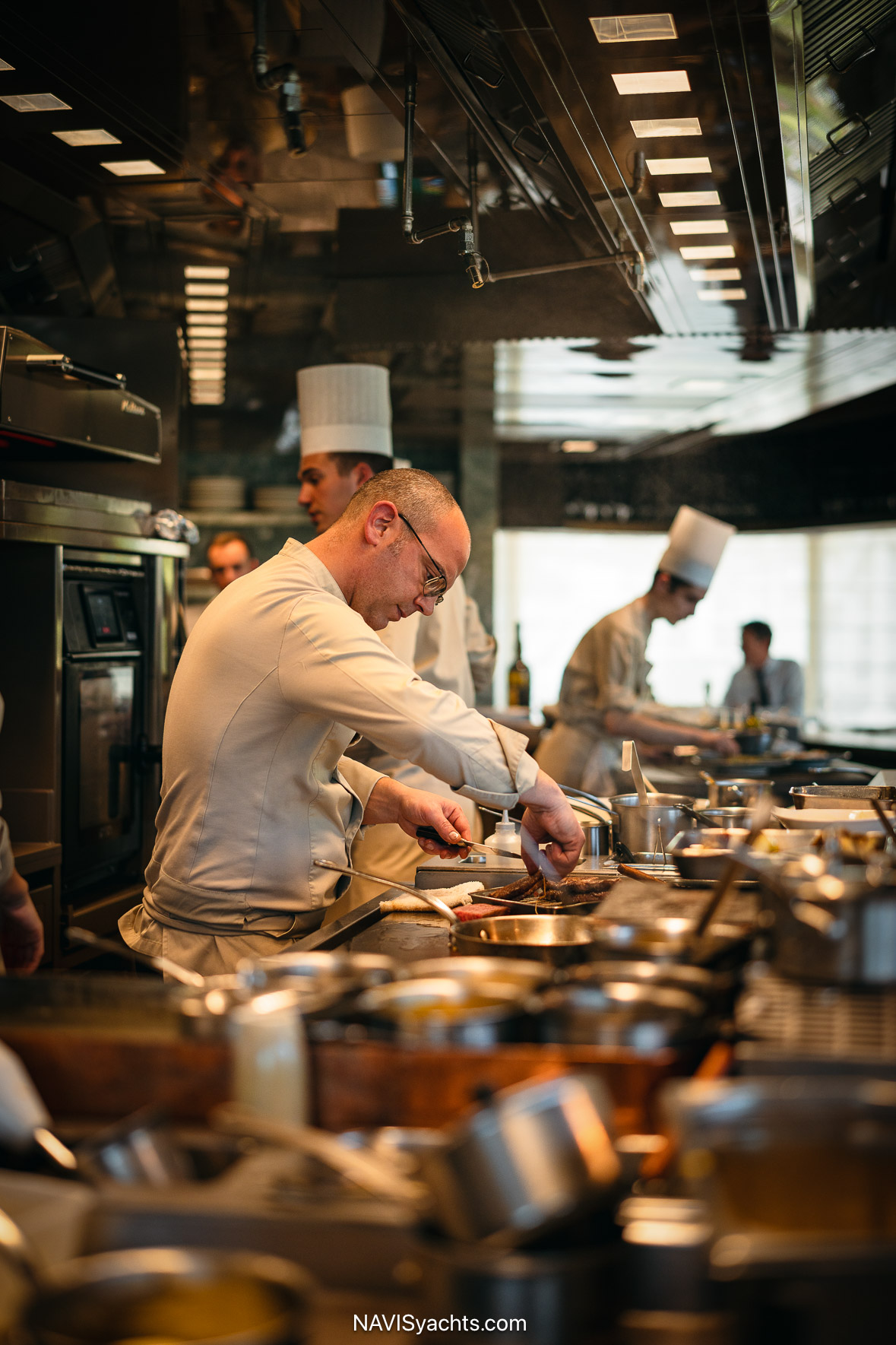 The metallic wood gastronomic bar at Pavyllon Monte-Carlo offering a front-row view of the open kitchen.